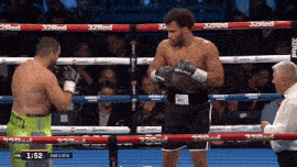 two men are boxing in a ring with a referee watching and the time is 1:52