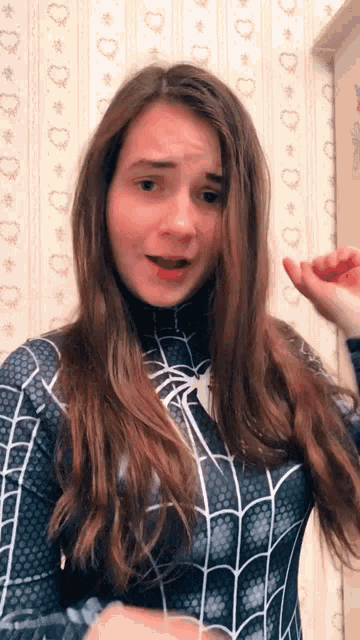 a woman is wearing a spiderman costume and making a face