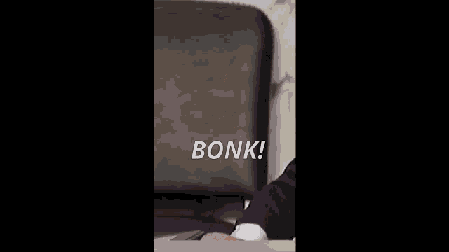 a man in a suit sits at a desk with a briefcase in the background and the word bonk written in white