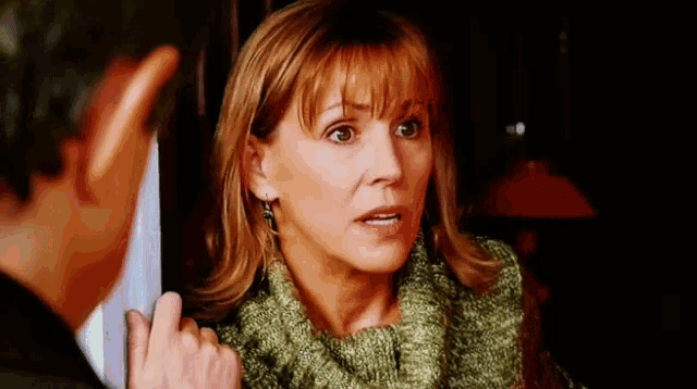 a woman wearing a green sweater is talking to a man .