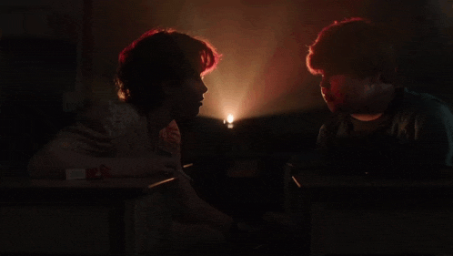 two people are sitting at a table with a light shining on them