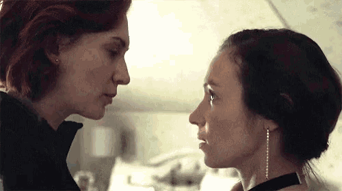 two women are looking at each other and touching their noses in a room .
