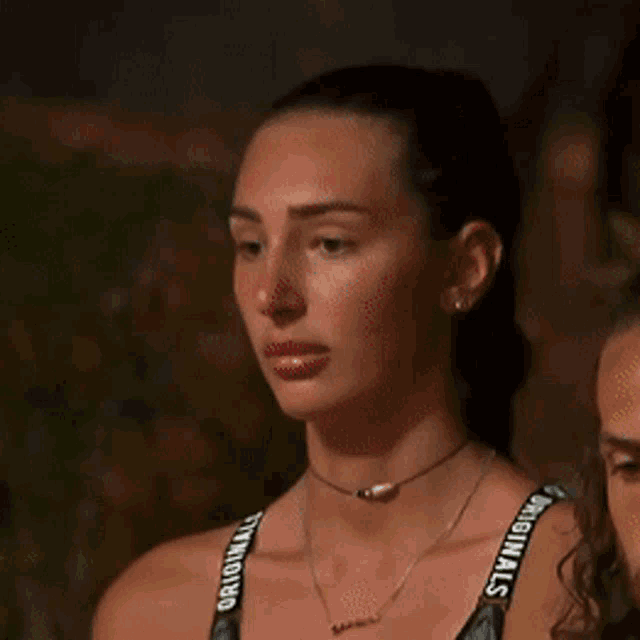 a woman with her eyes closed wearing a choker and a necklace with the word originals on the straps