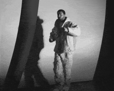 a black and white photo of a man in a white jacket and pants