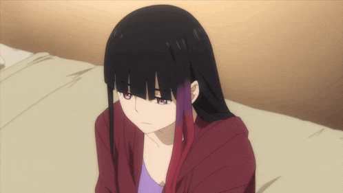a girl with long black hair and purple highlights is sitting on a bed