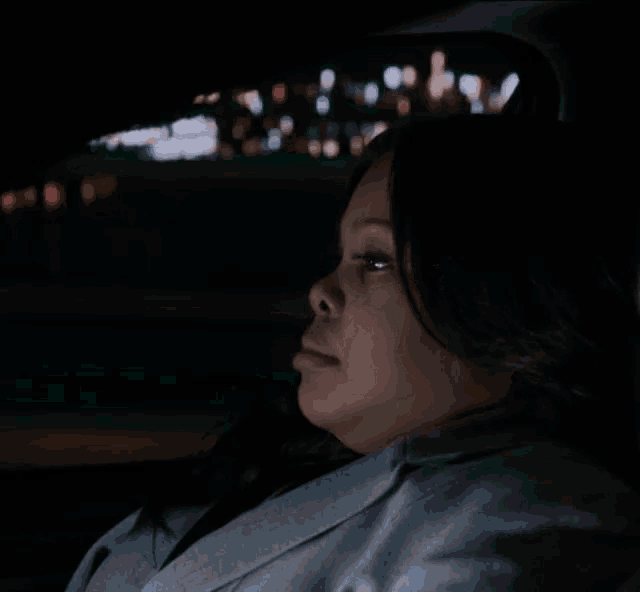 a woman is sitting in a car at night with her eyes closed