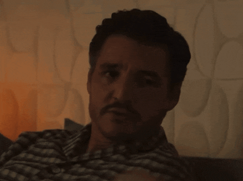 a man with a mustache sits on a couch