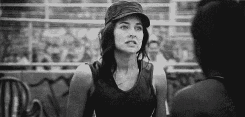 a black and white photo of a woman wearing a hat and talking to another woman .
