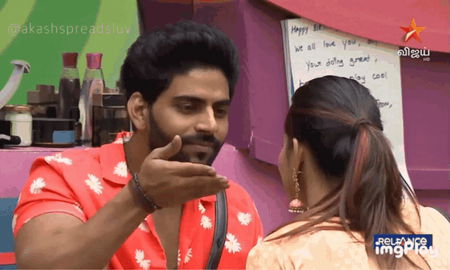 a man in a red shirt is talking to a woman in front of a sign that says " happy birthday "