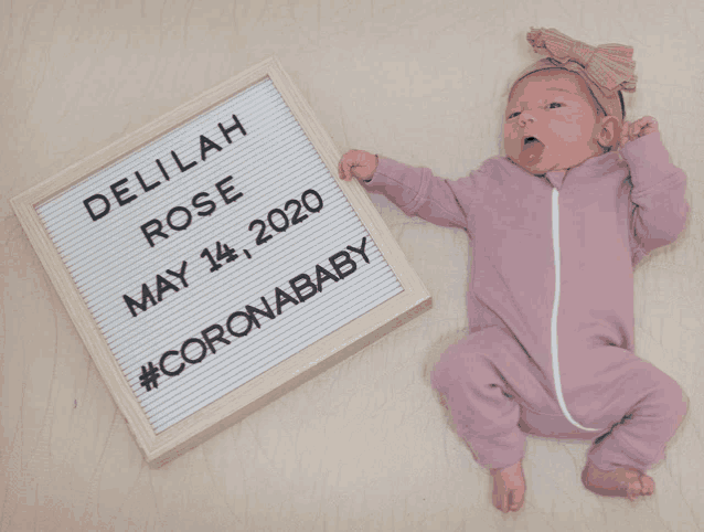 a newborn baby laying next to a sign that says delilah rose may 14 2020 #coronababy