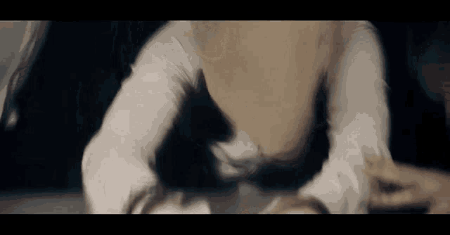 a person in a white shirt is laying on the floor with their hands on their knees .