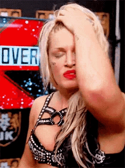 a woman is holding her hand to her forehead in front of a red sign that says over .
