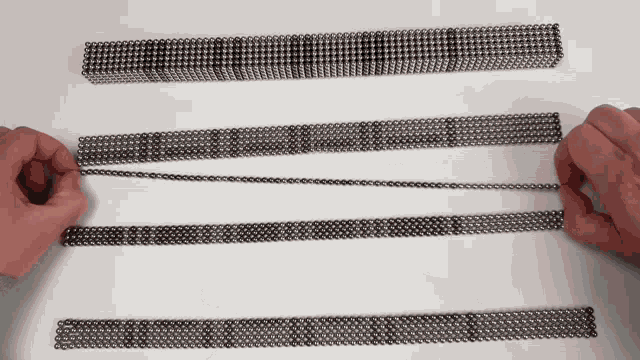a person is holding a string of metal balls