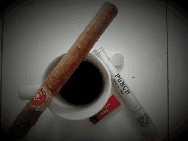 a cup of coffee next to a cigar and a tube that says punch