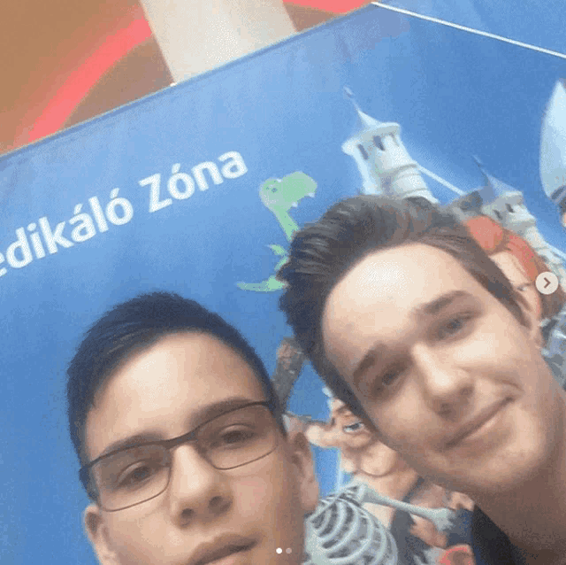 two young men are posing for a picture in front of a sign that says " dikalo zona "