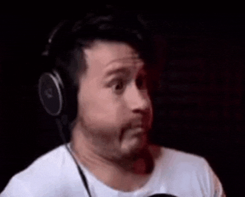 a man wearing headphones is sitting in front of a microphone and making a funny face .