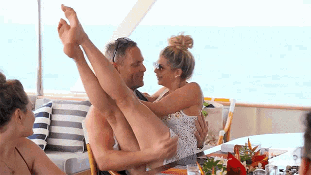 a man is holding a woman 's legs up in the air on a boat