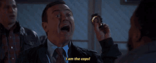 a man in a suit and tie holds a badge and says i am the cops