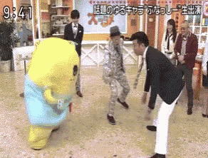 a group of people standing around a yellow stuffed animal with the time of 9:41 on the bottom