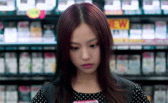 a woman is looking at her phone in front of a shelf that says new on it