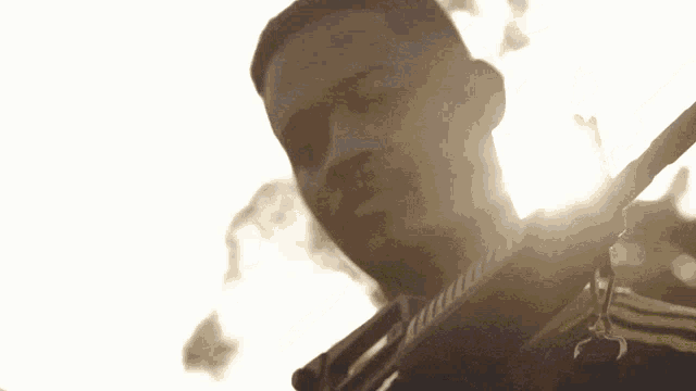 a close up of a man holding a gun with the sun shining through it