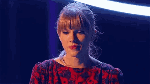a close up of a woman 's face with a blue background and a red dress .