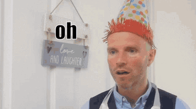 a man wearing a party hat stands in front of a love and laughter sign