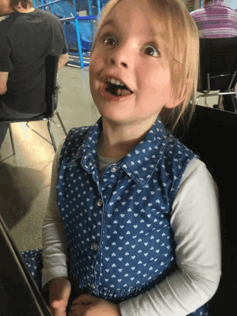 a little girl in a blue and white polka dot dress