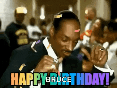 snoop dogg is wearing a suit and tie and holding a fork in his hand and says happy birthday .