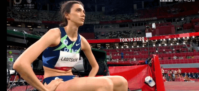a female athlete is sitting on a block in front of a tokyo 2020 sign