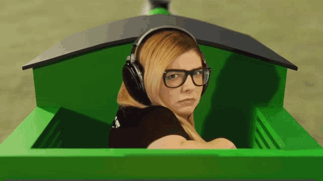 a woman wearing headphones and glasses is sitting in a green vehicle