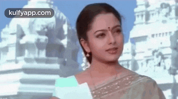 a woman is standing in front of a temple holding a piece of paper .