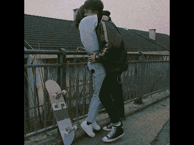a man and a woman are hugging while standing next to a skateboard that has the letter c on it