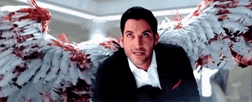 a man in a suit has bloody angel wings behind him