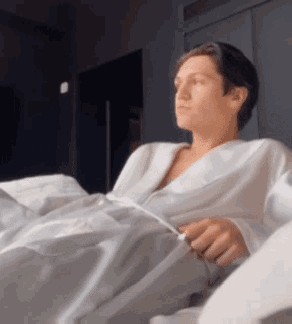 a man in a white robe is laying on a bed .