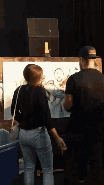 a man and a woman looking at a painting of a man and woman