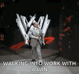 a man in a suit and tie is walking into work with a win sign behind him .