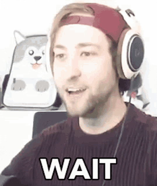a man wearing headphones and a hat is making a funny face while waiting .