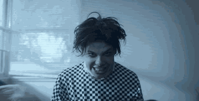 a man wearing a black and white checkered shirt is smiling