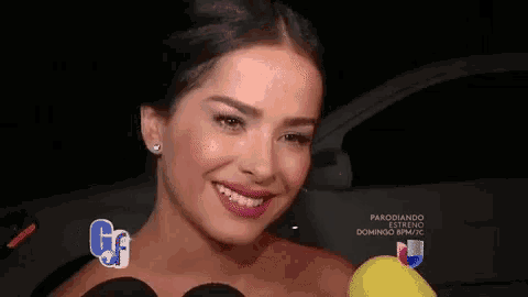 a woman is smiling while holding a yellow object in front of two microphones and a sign that says parodiando