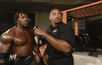 a shirtless wrestler is talking to another man