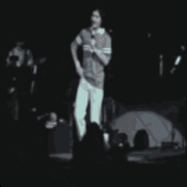 a man singing into a microphone on stage in front of a crowd