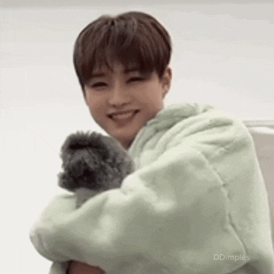 a young man is holding a small stuffed animal in his arms and smiling .