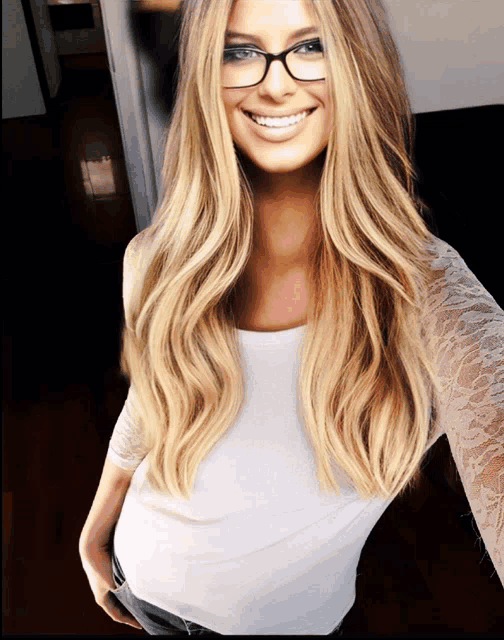 a woman wearing glasses and a white shirt is smiling