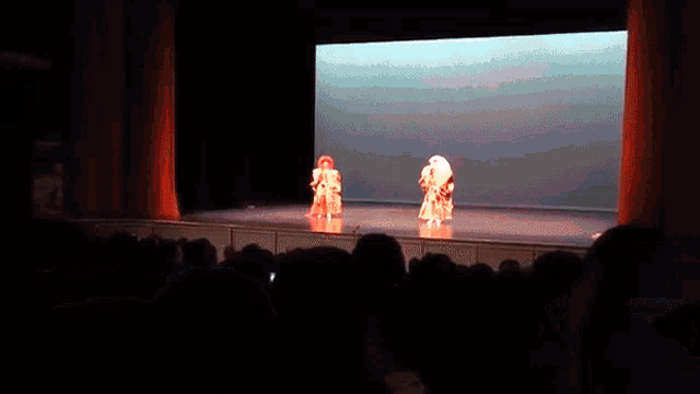 a couple of people on a stage with a large screen behind them