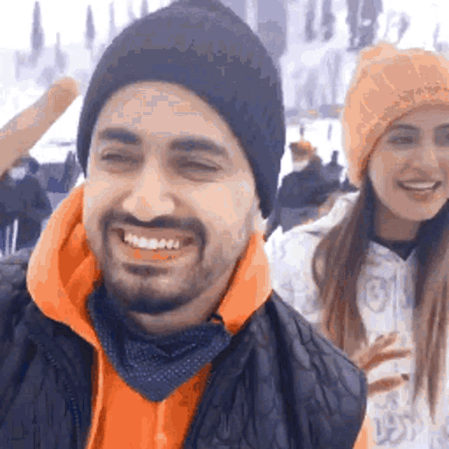 a man and a woman are smiling and looking at the camera .