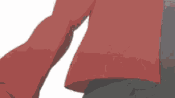 a person in a red shirt and black pants is standing on a white surface .