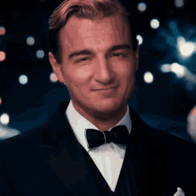 a man wearing a tuxedo and bow tie smiles for the camera