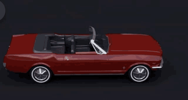 a red mustang convertible with the top down on a dark background