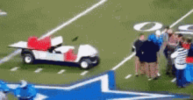 a golf cart is on a football field with people watching